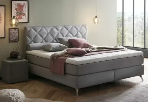 Modernes Boxspringbett in hellem Schlafzimmer mit großen Fenstern und stilvoller Dekoration.