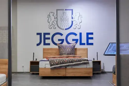 Modernes Schlafzimmer mit Holzbett, Nachttischen und dekorativen Kissen im Jeggle-Showroom.