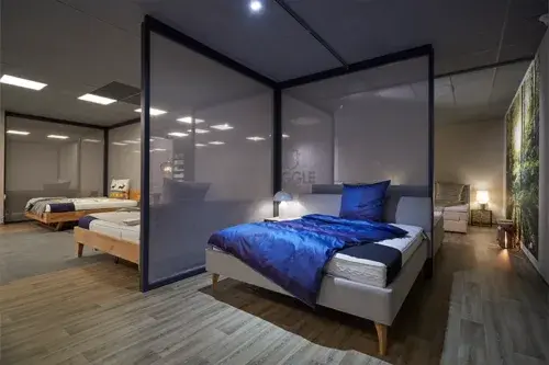 Modernes Schlafzimmer mit Doppelbett, blauer Bettwäsche und stilvoller Beleuchtung im Möbelhaus.