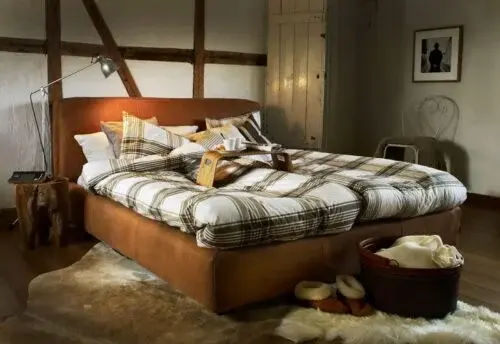 Gemütliches Schlafzimmer mit modernem Boxspringbett, kariertem Bettbezug und Holzdekor.