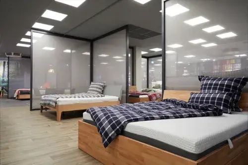 Helles Schlafzimmer mit modernen Holzbetten, Matratzen und karierten Bettbezügen im Möbelhaus.